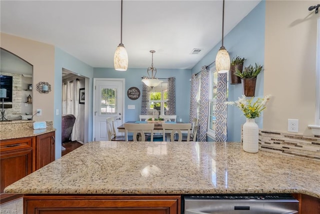 kitchen with brown cabinets, light stone countertops, hanging light fixtures, dishwasher, and visible vents