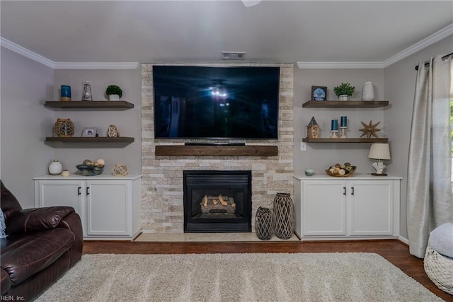 living area featuring a stone fireplace, ornamental molding, and wood finished floors
