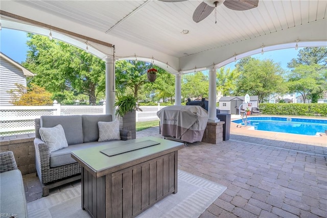 view of patio / terrace with an outdoor structure, a grill, a fenced in pool, a ceiling fan, and a storage shed