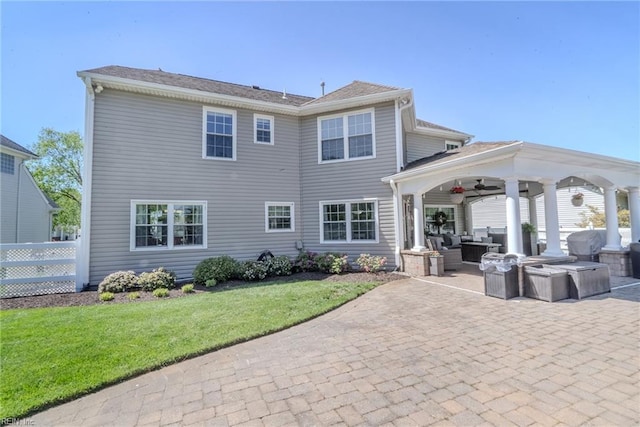 rear view of property featuring fence, outdoor lounge area, a patio area, a ceiling fan, and a yard