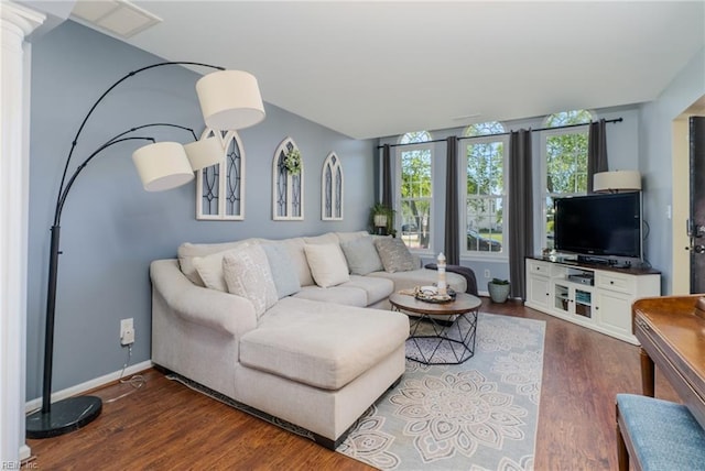 living area with baseboards, decorative columns, lofted ceiling, and wood finished floors