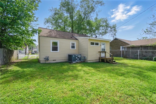 rear view of property with a lawn, a fenced backyard, central air condition unit, and crawl space