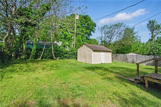 view of yard with an outdoor structure, fence, and a storage shed