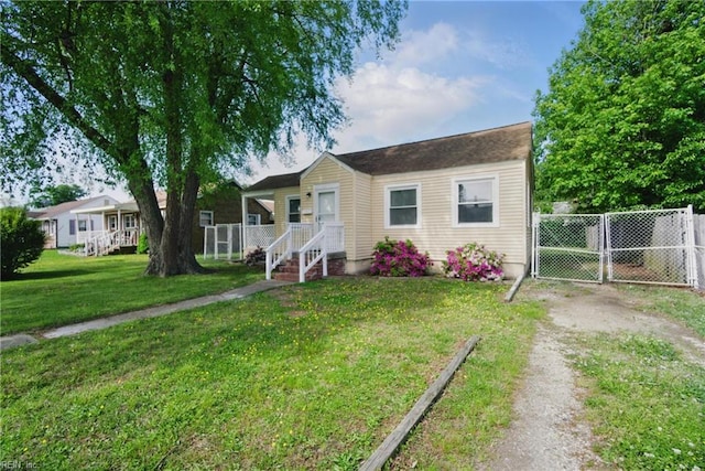 view of front of home with fence, a gate, dirt driveway, and a front yard