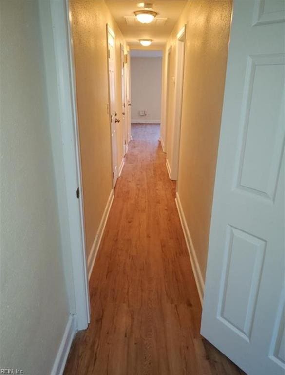 corridor featuring wood finished floors and baseboards