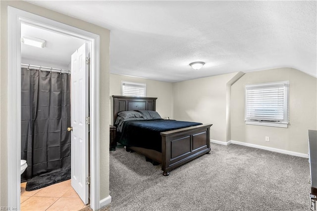 carpeted bedroom featuring a textured ceiling, baseboards, and vaulted ceiling