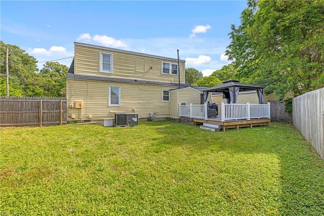 back of house featuring central air condition unit, a wooden deck, a gazebo, and a lawn