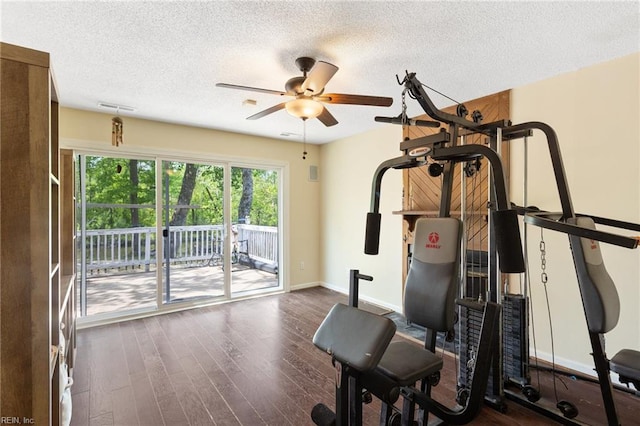 exercise area with baseboards, a ceiling fan, a textured ceiling, and wood finished floors