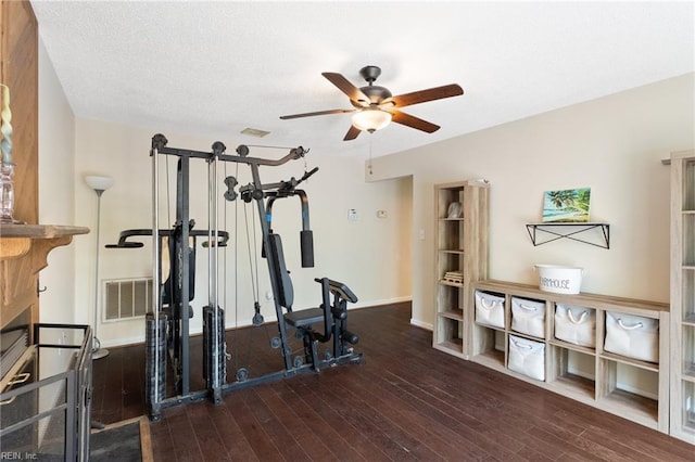 workout room featuring baseboards, wood-type flooring, a ceiling fan, and visible vents