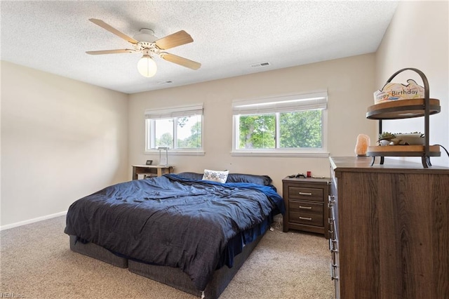 bedroom with visible vents, a textured ceiling, and light carpet