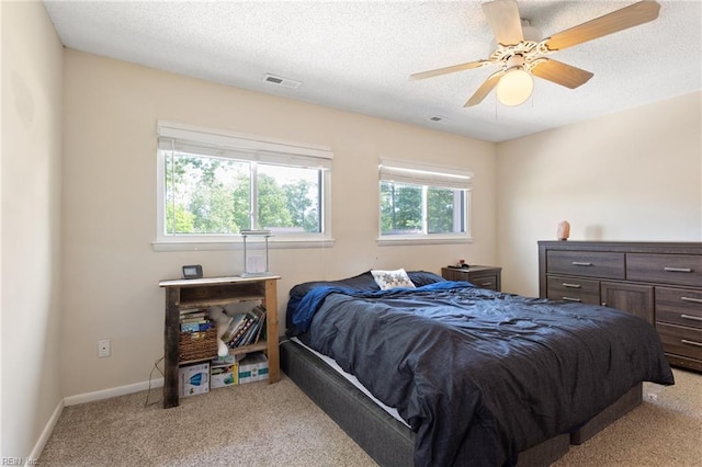 bedroom featuring ceiling fan, light colored carpet, a textured ceiling, and visible vents