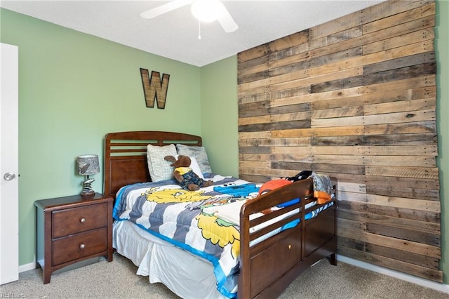 bedroom with carpet flooring, ceiling fan, and wood walls
