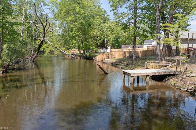 view of dock with a water view and fence
