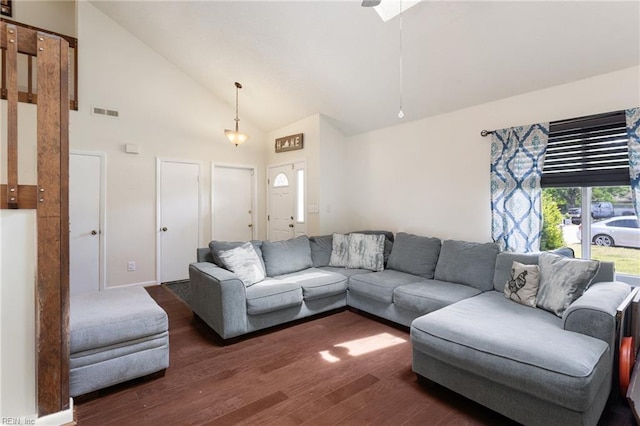 living area featuring dark wood-style flooring, high vaulted ceiling, and visible vents
