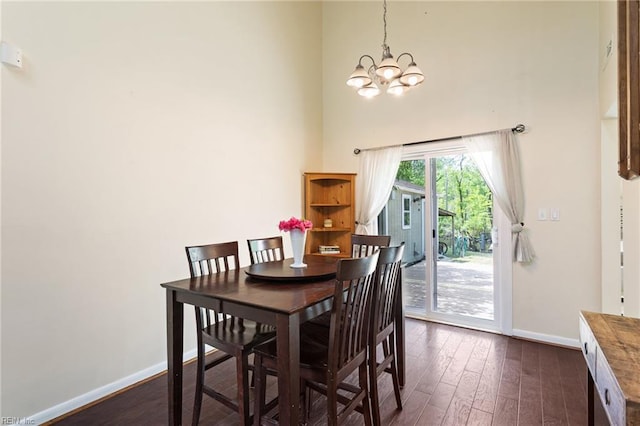 dining room with dark wood-style flooring, baseboards, an inviting chandelier, and a high ceiling