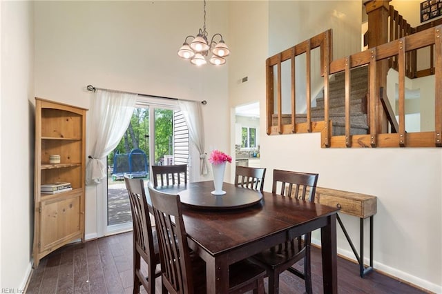 dining area with visible vents, dark wood-style flooring, a high ceiling, and a notable chandelier