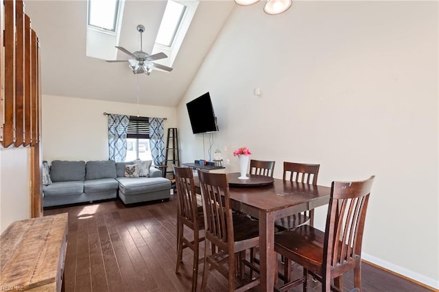 dining area featuring baseboards, ceiling fan, dark wood-style floors, high vaulted ceiling, and a skylight