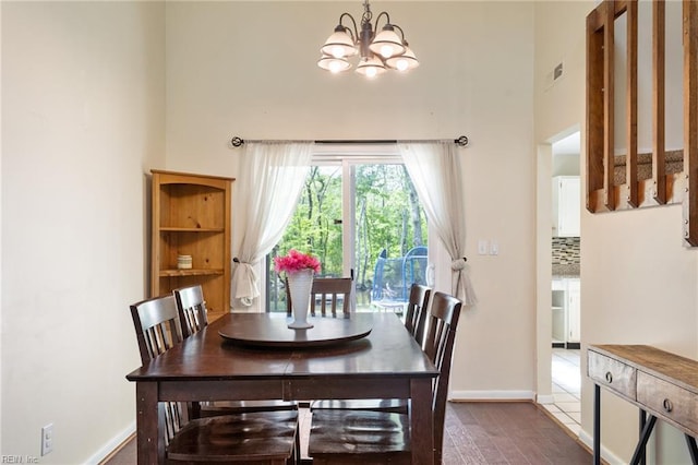 dining space featuring baseboards, an inviting chandelier, visible vents, and a towering ceiling