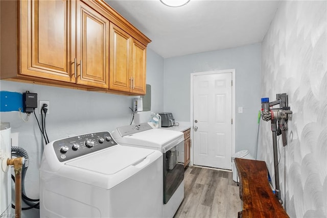 washroom featuring separate washer and dryer, light wood finished floors, and cabinet space