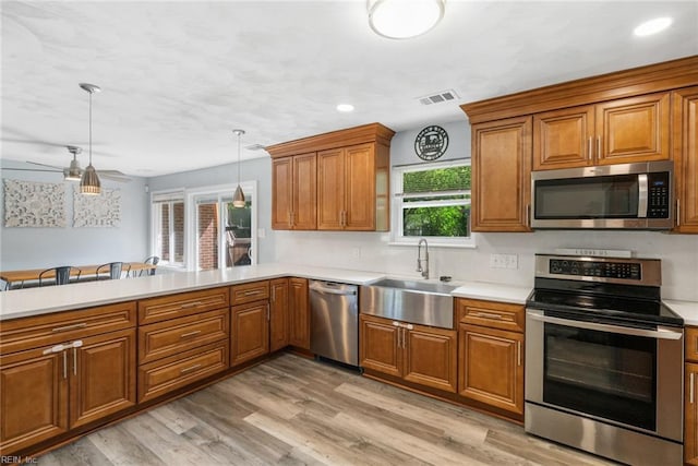 kitchen with a sink, appliances with stainless steel finishes, brown cabinets, and light countertops