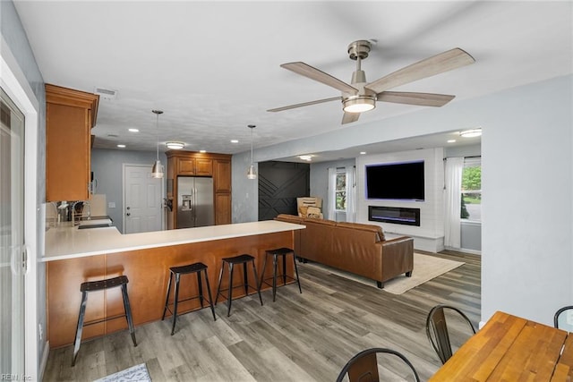 kitchen featuring stainless steel fridge, light countertops, light wood-type flooring, and a peninsula