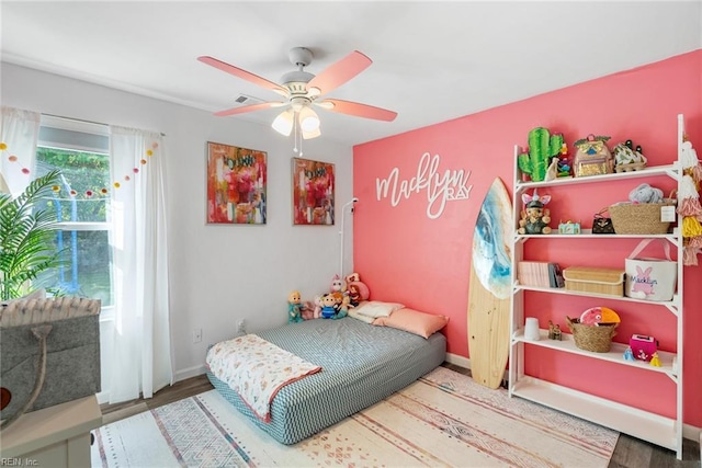 bedroom with baseboards, visible vents, ceiling fan, and wood finished floors