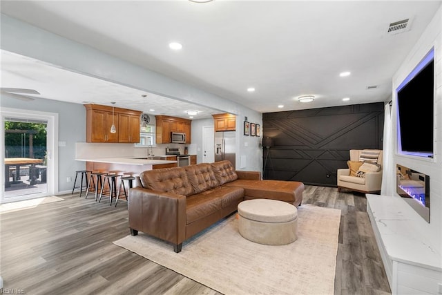 living area featuring recessed lighting, baseboards, light wood-type flooring, and visible vents