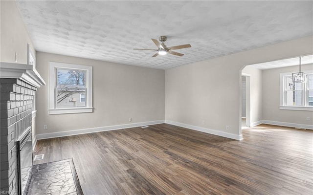 9254 Marlow Ave, Norfolk, VA 23503 - unfurnished living room with ceiling fan with notable chandelier, baseboards, a brick fireplace, and dark wood-style flooring