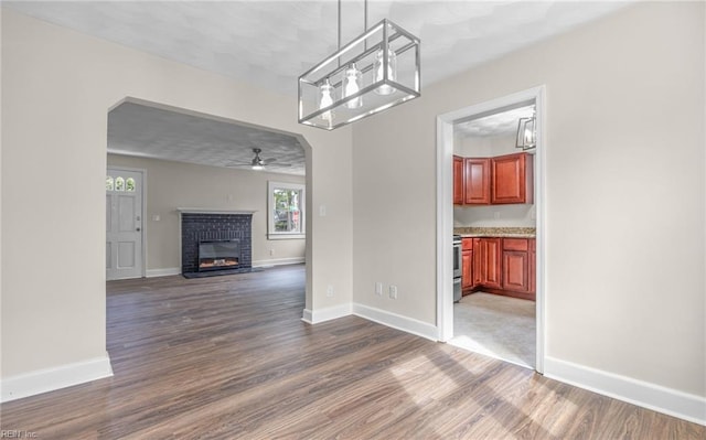 9254 Marlow Ave, Norfolk, VA 23503 - unfurnished dining area with baseboards, a fireplace, a ceiling fan, and dark wood-style flooring