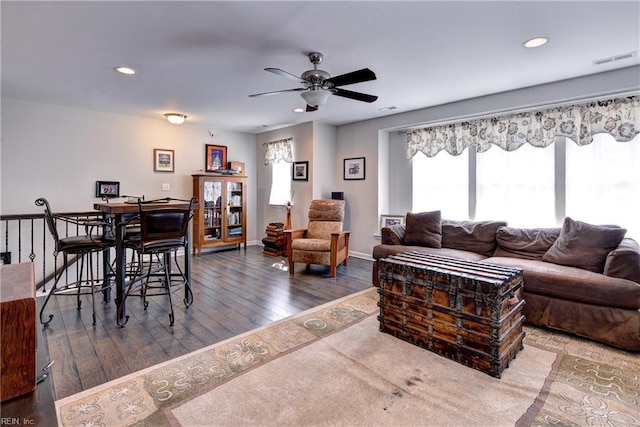 living area featuring a wealth of natural light, wood-type flooring, a ceiling fan, and visible vents
