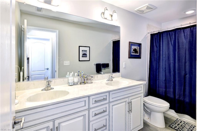 bathroom featuring double vanity, toilet, visible vents, and a sink