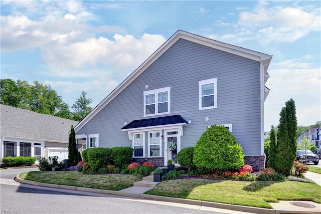 traditional home with stone siding, a garage, a front yard, a standing seam roof, and metal roof