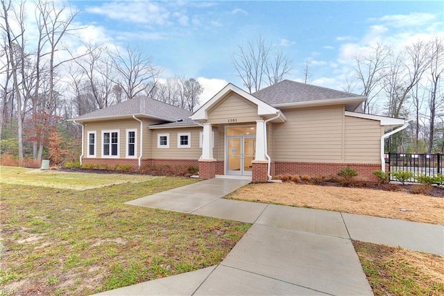 view of front of house featuring brick siding, fence, and a front yard