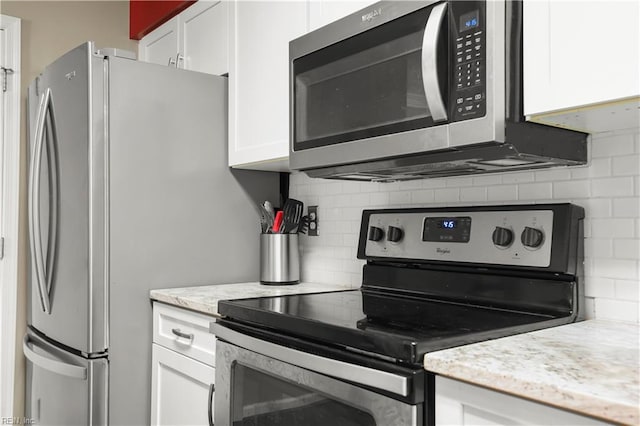 kitchen featuring light stone counters, decorative backsplash, stainless steel appliances, and white cabinetry