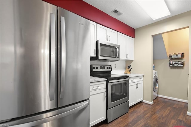 kitchen featuring stainless steel appliances, visible vents, white cabinetry, and washer / dryer