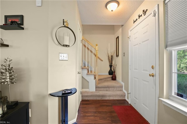entrance foyer featuring baseboards, dark wood-style floors, a textured ceiling, and stairs