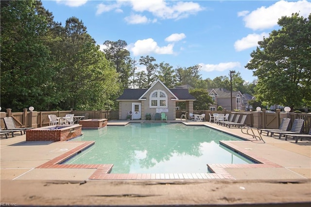 community pool with an exterior structure, fence, an outdoor structure, a patio, and a fire pit