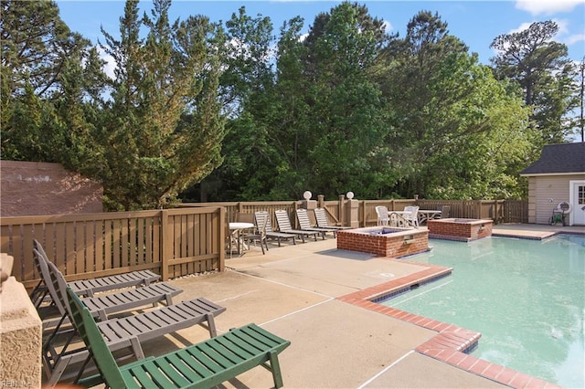 view of swimming pool featuring a patio, a pool with connected hot tub, and a fire pit