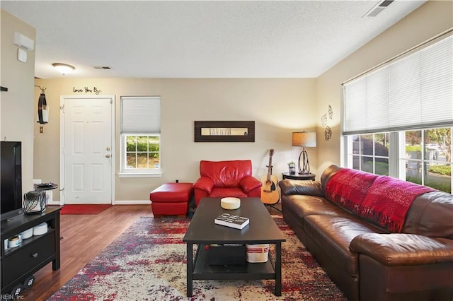 living area with baseboards, visible vents, and wood finished floors