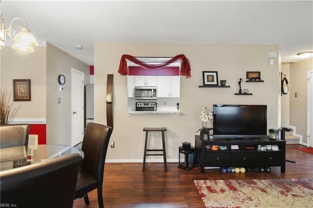living room with baseboards, wood finished floors, and a notable chandelier