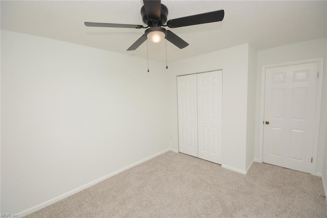 unfurnished bedroom with baseboards, ceiling fan, carpet, and a closet