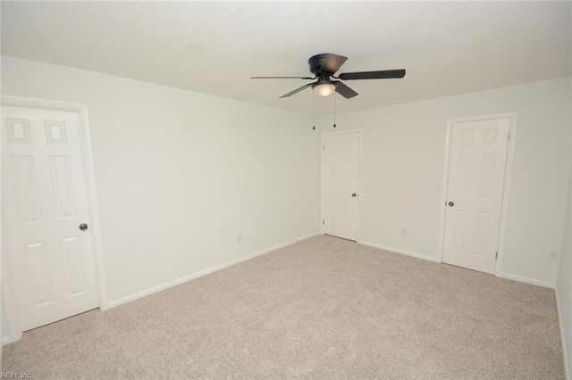 spare room with ceiling fan, light colored carpet, and baseboards