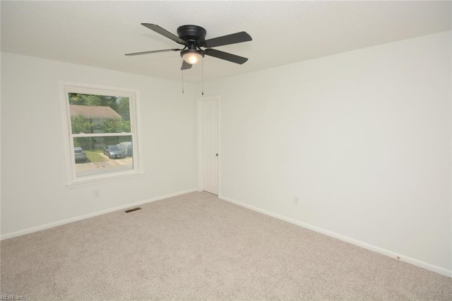 carpeted empty room with ceiling fan, visible vents, and baseboards