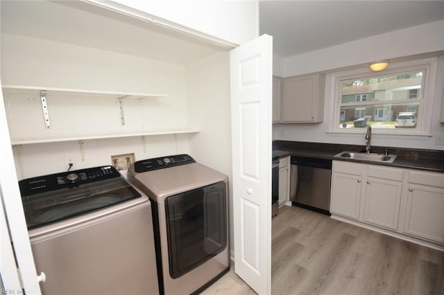 washroom with laundry area, a sink, light wood finished floors, and separate washer and dryer