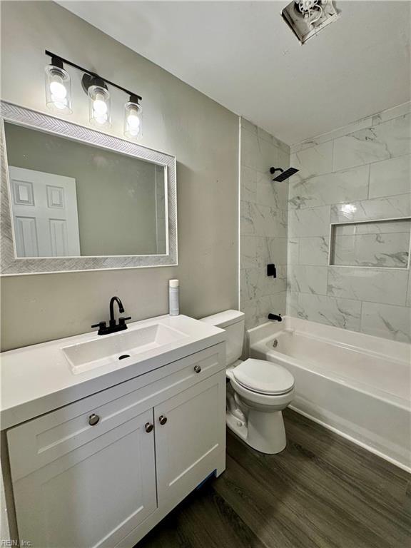 bathroom featuring wood finished floors, toilet, bathing tub / shower combination, and vanity