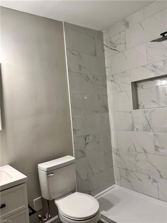 full bathroom featuring a stall shower, toilet, and vanity