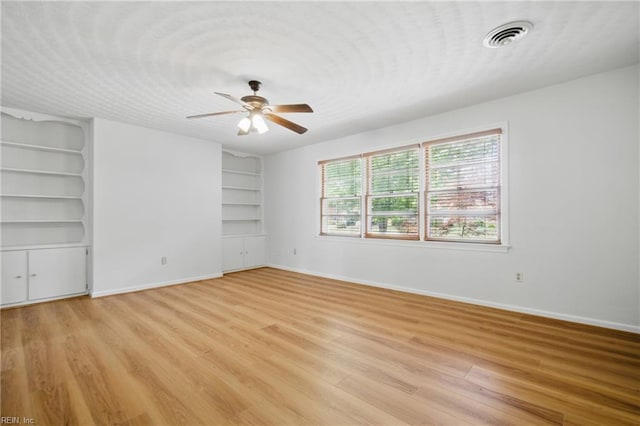 interior space featuring a ceiling fan, visible vents, built in features, baseboards, and light wood finished floors