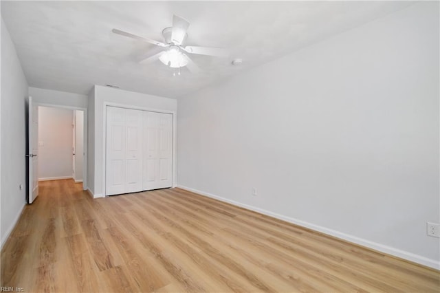 unfurnished bedroom featuring baseboards, a ceiling fan, light wood finished floors, and a closet