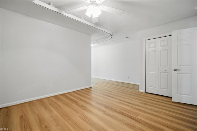 interior space with baseboards, a ceiling fan, and light wood finished floors