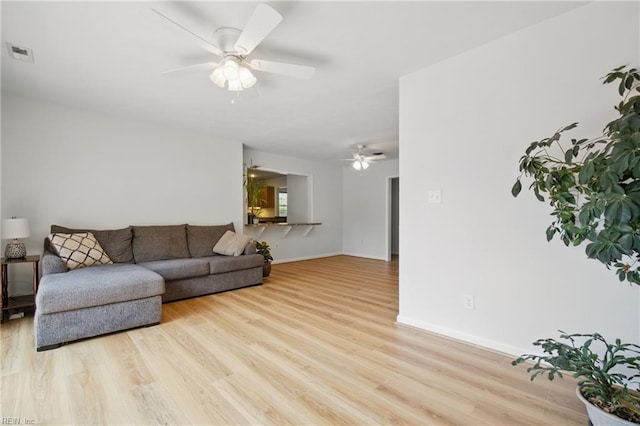 living room with a ceiling fan, baseboards, visible vents, and light wood-style floors